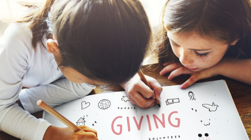 Two children writing the word giving