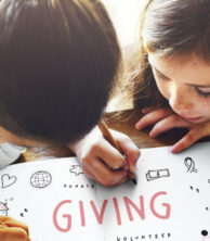 Two children writing the word giving